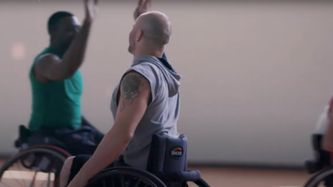 A man in a wheelchair with his arm raised.