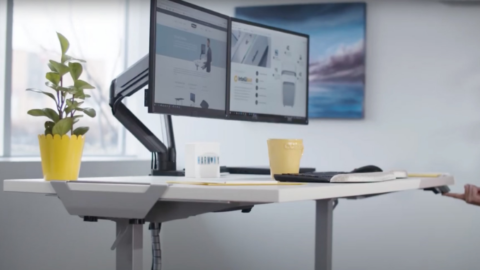A desk with two monitors and a cup on it