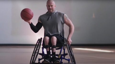 A man in a wheelchair holding a basketball.