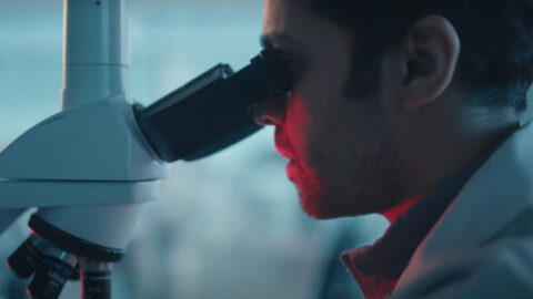A man looking through a microscope at something