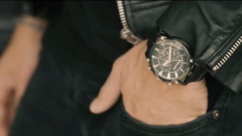 Close-up of a man's wrist wearing a stylish watch with a large black dial, partially covered by the sleeve of a leather jacket.